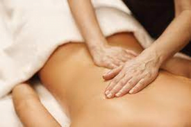 Ağrıyı hafifletmek için müvekkilinin vücuduna masaj yapan bir masaj terapisti.